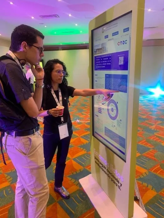 Investigador presentando su póster en un tótem digital