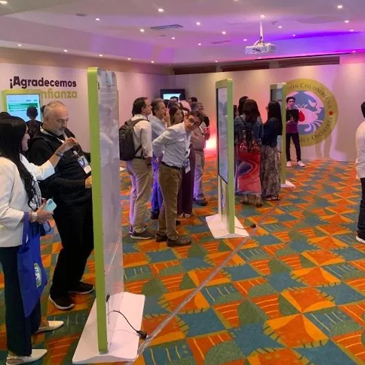 Grupo de asistentes conversando frente a los tótems de pósters